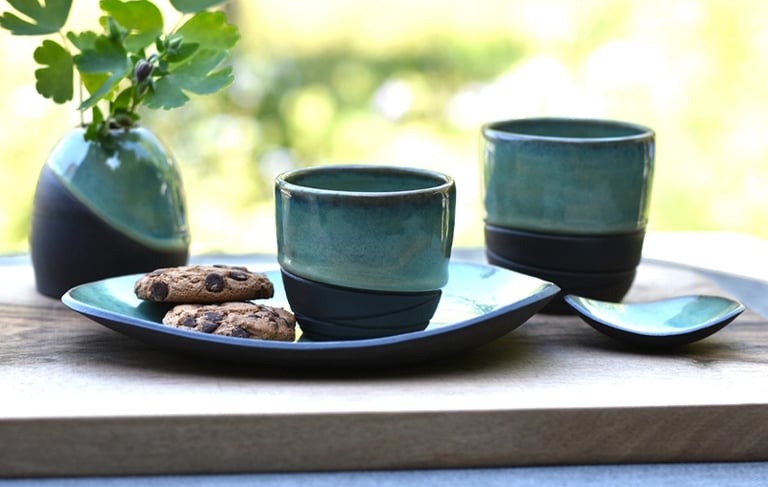 Koffie en theekopjes met schoteltjes en vaasje van handgemaakte keramiek
