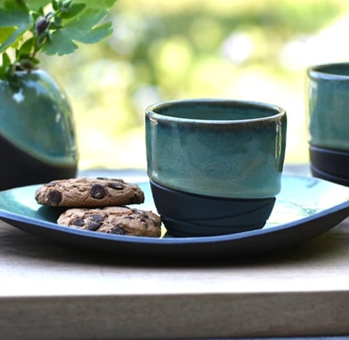 Koffie en theekopjes met schoteltjes en vaasje van handgemaakte keramiek