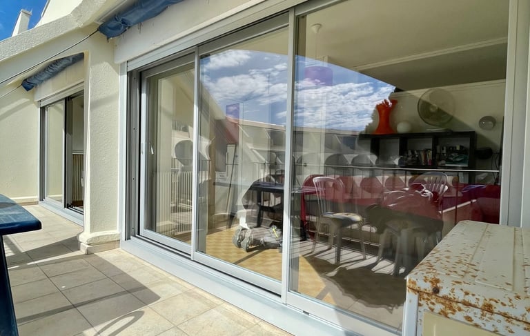 Baies vitrées avec systèmes coulissants pour l'accès à la terrasse d'un appartement.