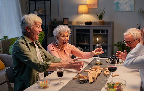Pensioners having fun with friends in the evening, playing Jenga