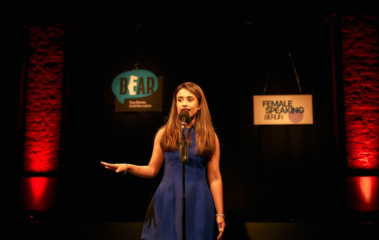 Confident woman speaking on stage, telling a story to an audience in a theatre