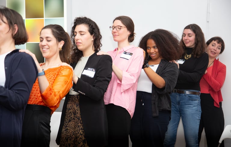Women standing in a line with hands on each other’s backs, showing mutual support and connection