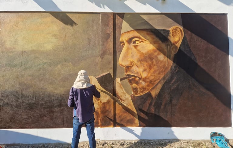 An artist creates a large street art mural of an indigenous shaman smoking a pipe