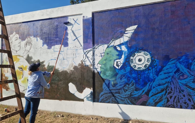 Artist uses a paint roller on a ladder to create a vibrant mural at Centro Recreacional Mokanranko 