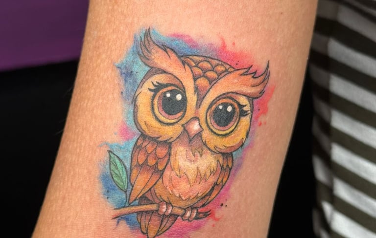 Small owl tattoo on the arm of a woman. 