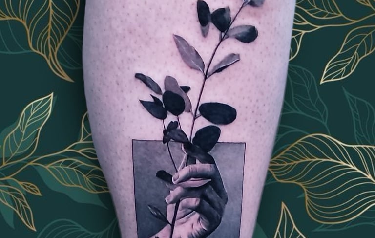 a person's hand holding a plant with leaves. custom piece by Katarsis Tattoo Perú.
