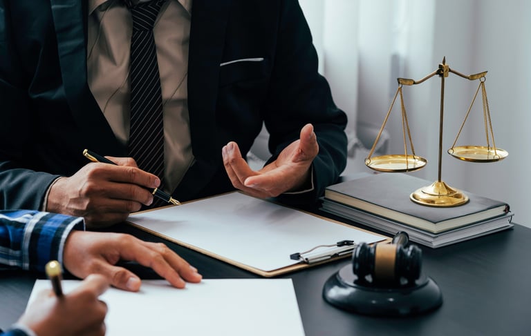 Professional lawyer in a suit providing legal advice to a client with a gavel and scales of justice on the desk.