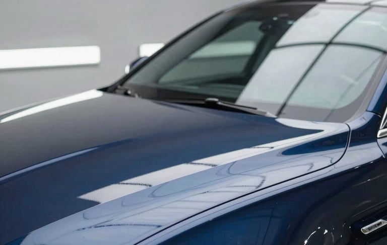 Professional car detailing setting in North American / US, shining clean car surface reflecting light, modern garage, colors like dark blue and light gray, elegant, high quality photography.