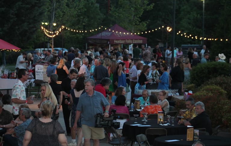 Crowd at the Paradise Chocolate Festival event with string lights and vending tables.