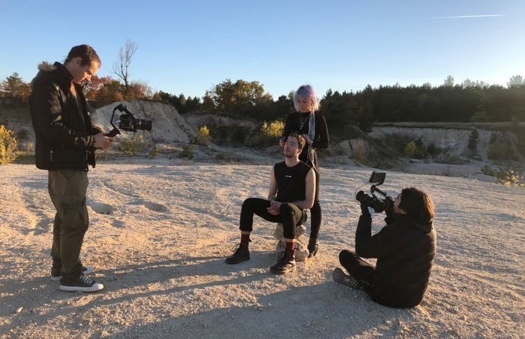 a man is filming a video of a man in a black shirt for youtube