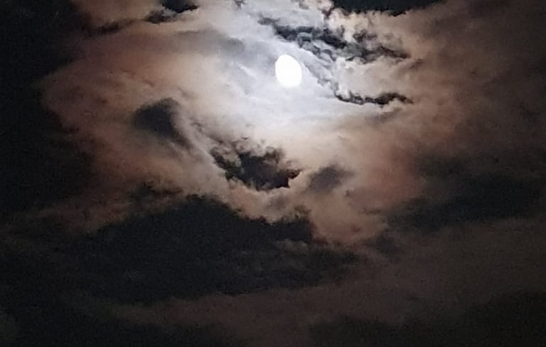 a full moon in the sky with clouds shot during night boat tour