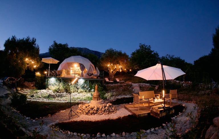 Osvetljeni glamping kupola i dvorište u večernjoj atmosferi