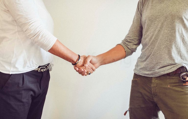 two men shaking hands with a woman in a white shirt