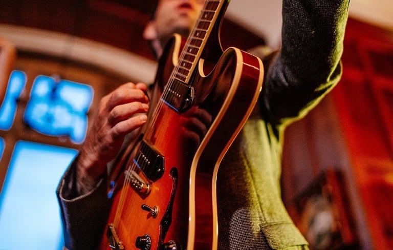 a man holding a guitar and playing a guitar