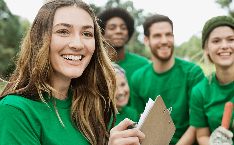 a woman in green shirt holding a clipboard and smiling