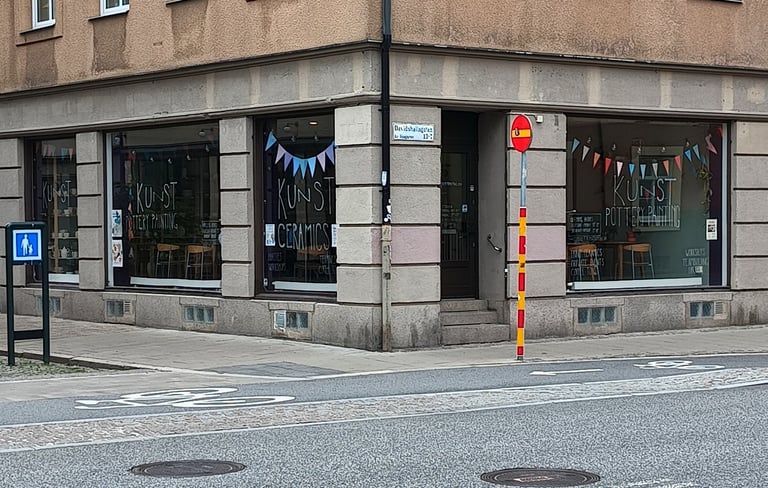 Pottery painting cafe storefront windows showing chairs and tables inside.