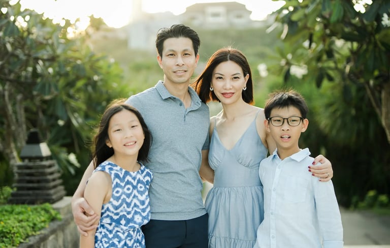 Family portrait surrounded by lush tropical gardens during a luxury family photography session at The Ritz-Carlton Bali.