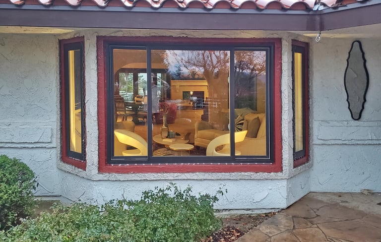 View of living room from outside a set of new Bronze bay windows.