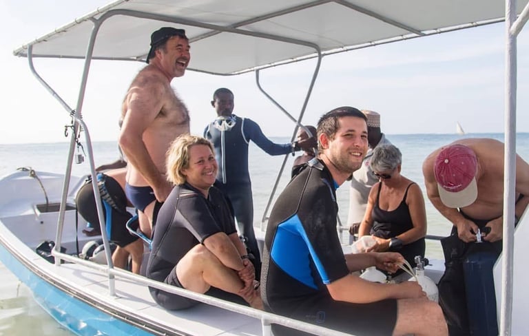 Smiling divers in wetsuits on a boat preparing for a scuba diving excursion in the ocean.