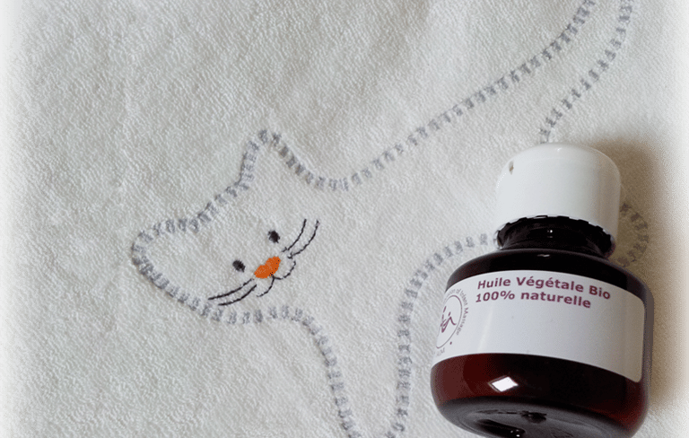 Flacon d'huile de massage posé sur un dessin de chat