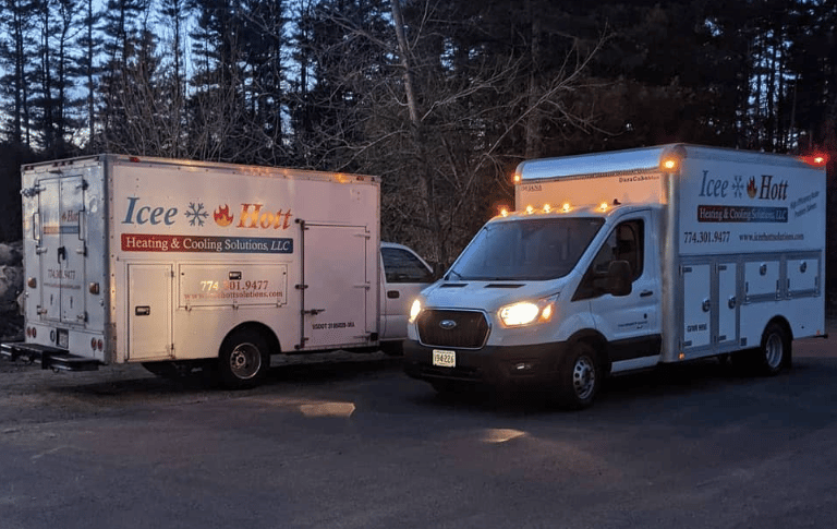 Two Icee Hott Heating & Cooling Solutions service trucks parked at dusk for HVAC maintenance.