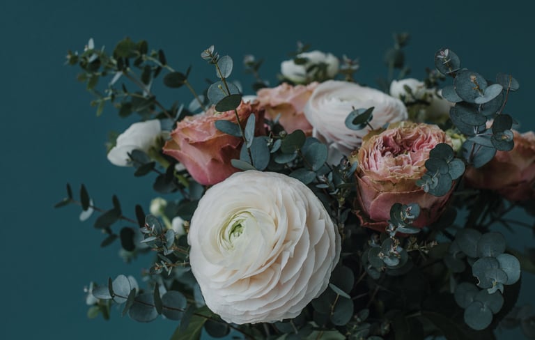 Joli bouquet de fleurs renoncule, roses et eucalyptus sur fond bleu canard