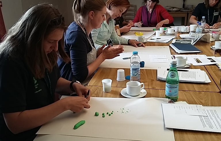 group of adults at a table with paper and modelling clay