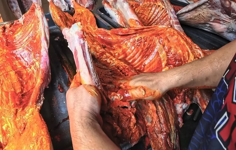 a man is holding a bunch of meat on a table