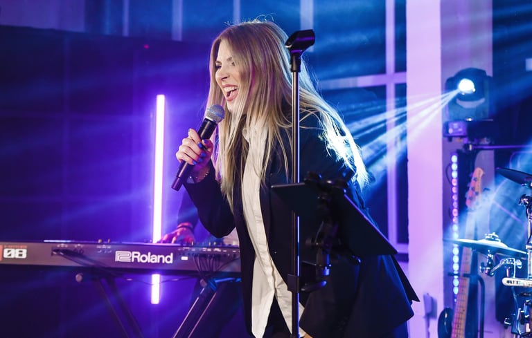 a woman in a black suit singing on the stage