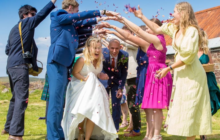 a bride and groom and guests throwing confetti