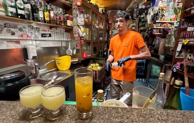 A bartender serves poncha fruit cocktails and drinks in a rustic, vintage-style bar.