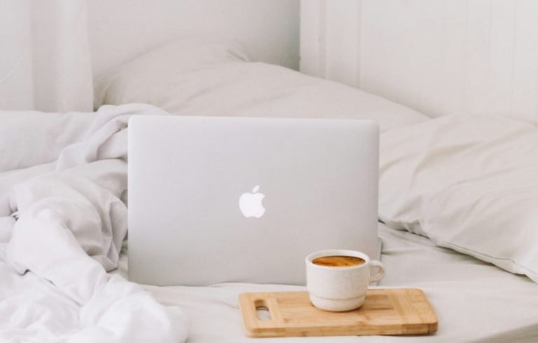 laptop on bed with coffee