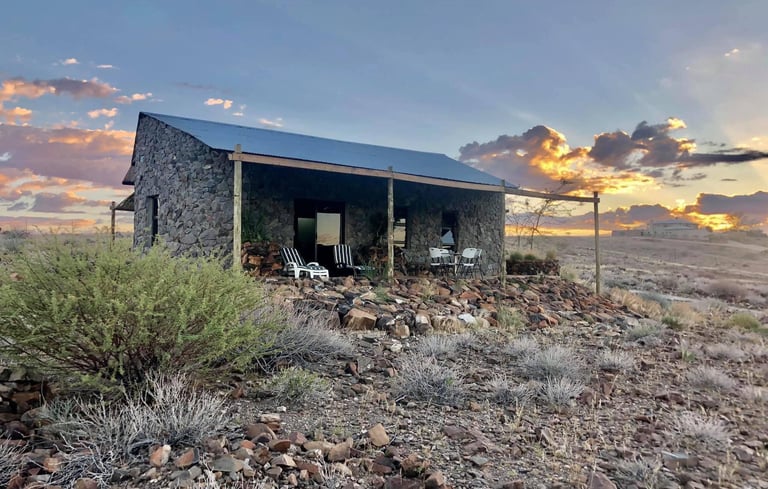 a small stone building with a blue sky and clouds in uis namibia