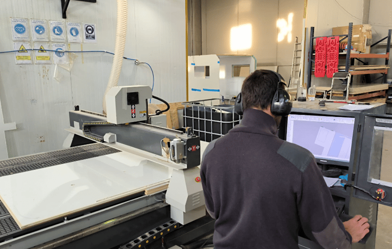 a man in a factory with a machine that is cutting into a sheet