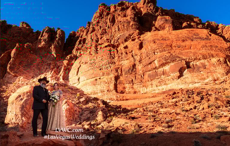 a bride and groom standing on a rocky cliff