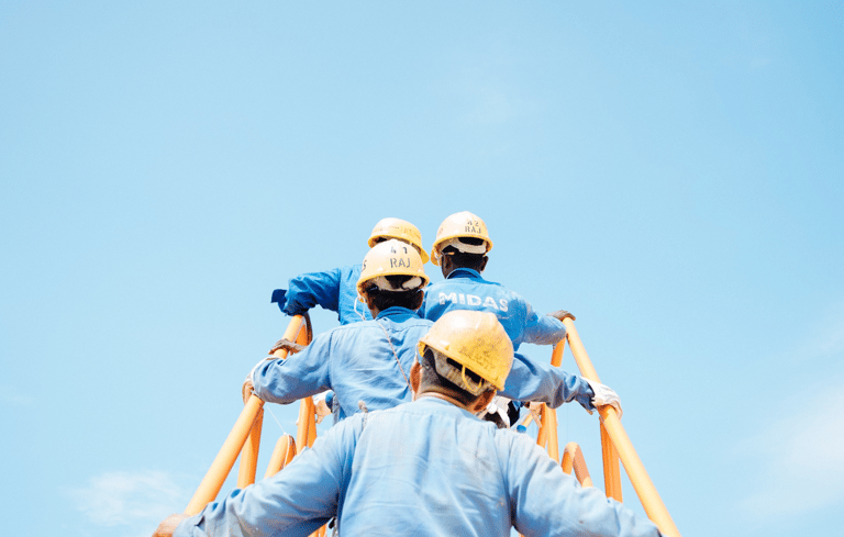 two men in blue workwears and helmets on a ladder ladder