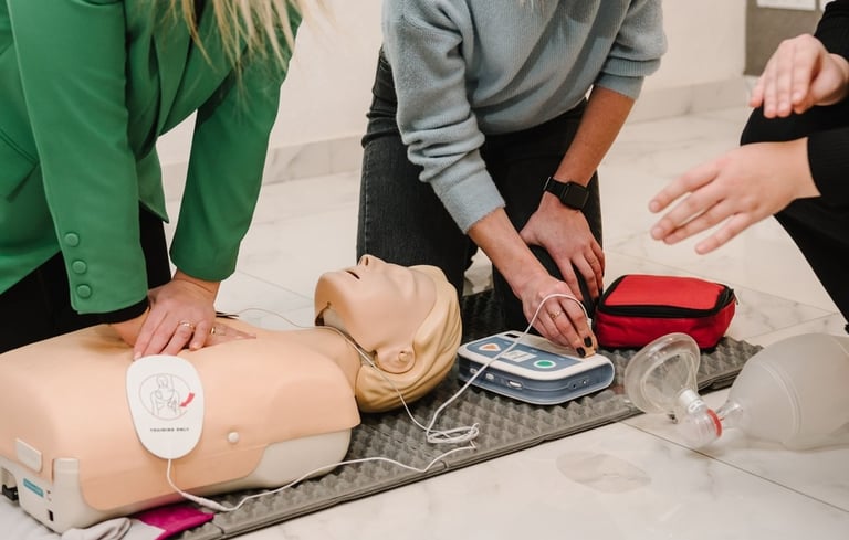 Two women administering CPR training on a CPR dummy in a training