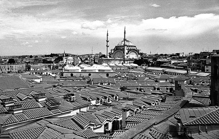 Black-and-white view over the domed rooftops of Istanbul's Grand Bazaar, with the Nuruosmaniye Mosqu