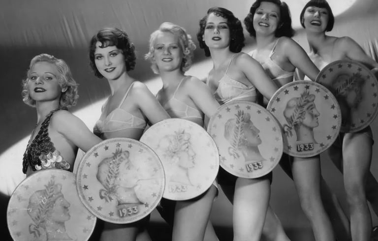 Low‑angle shot of Gold Diggers of 1933 chorus girls holding giant coins in “We’re in the Money.”