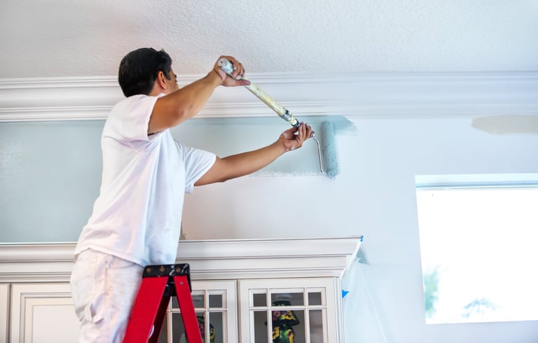 a man is painting a ceiling with a paint roller