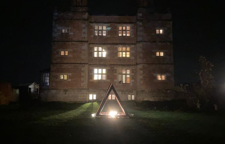 Soulton Hall seen at night with a large, steel pyramid in front