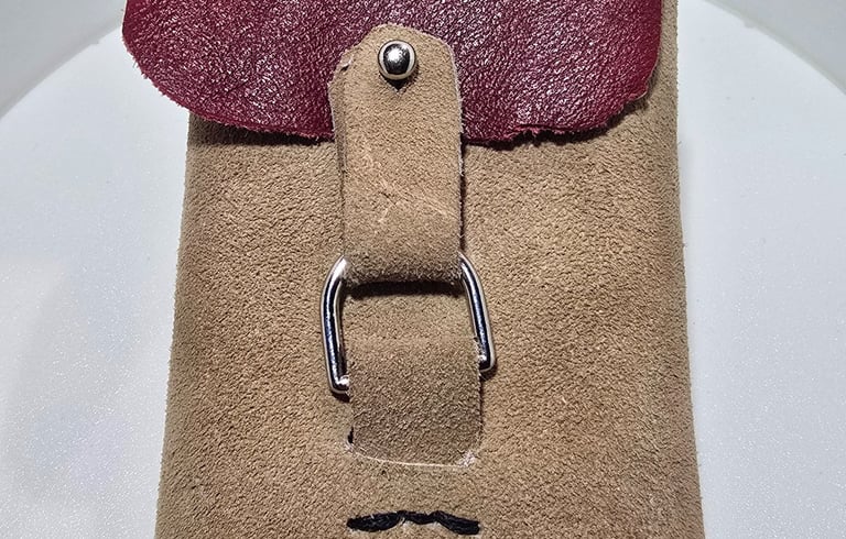 Handmade tan leather pouch with a dark red flap and silver metal buckle closure.
