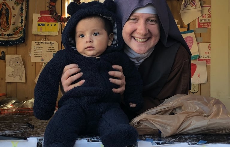 A Franciscan Daughter of Mary and a very cute baby pose for a picture at the Rose garden Mission