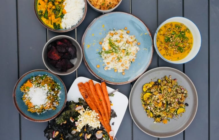 a table with bowls of vegetarian plant-based food and a bowl of vegetables carrots chickpeas