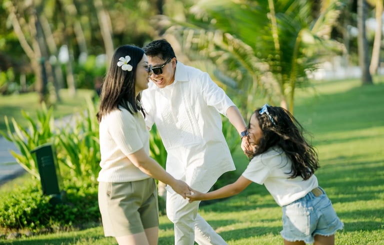 Parents and daughter sharing a playful moment in the tropical gardens of InterContinental Bali Resort