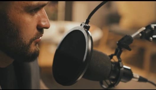 a man in a recording studio with a microphone and a microphone