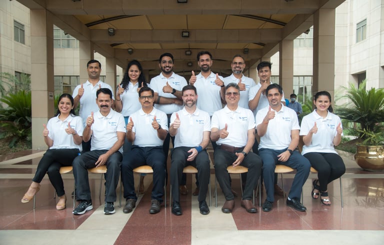 A diverse group of people smiles and gives thumbs-up signs in a team photograph.