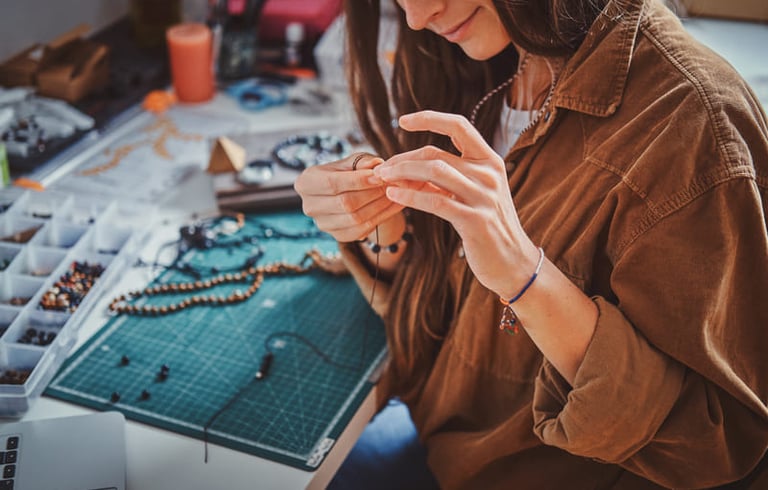  Un joyero en una mesa de manualidades ensamblando un collar de cuentas hecho a mano