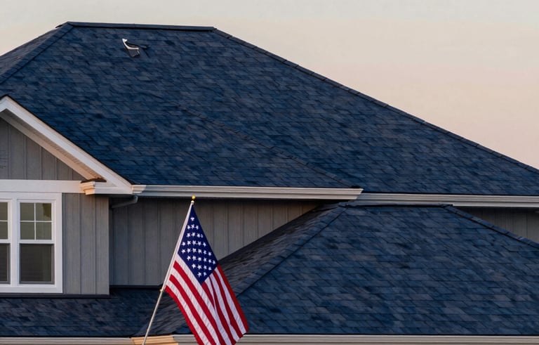 A reliable and sturdy home exterior in North American / US style with a newly installed dark blue roof. The lighting is the golden hour of sunset, highlighting the textures of the roof. In the yard, an American flag is neatly displayed on a pole, conveying patriotic pride. North American / US.