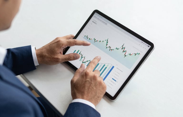 Top-down view of a professional South American / Brazilian business person working on a tablet with financial charts in a bright, clean office with deep blue accents, conveying precision and trust.